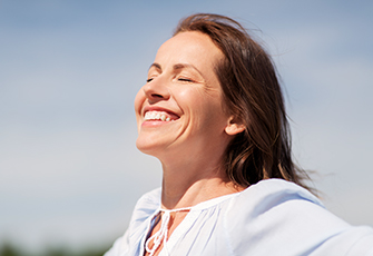 Femme souriante profitant du soleil, source de vitamine D