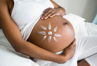 femme enceinte appliquant une crème solaire haute protection