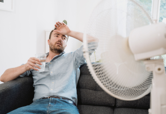 Homme face à un ventilateur souffrant de chaleur